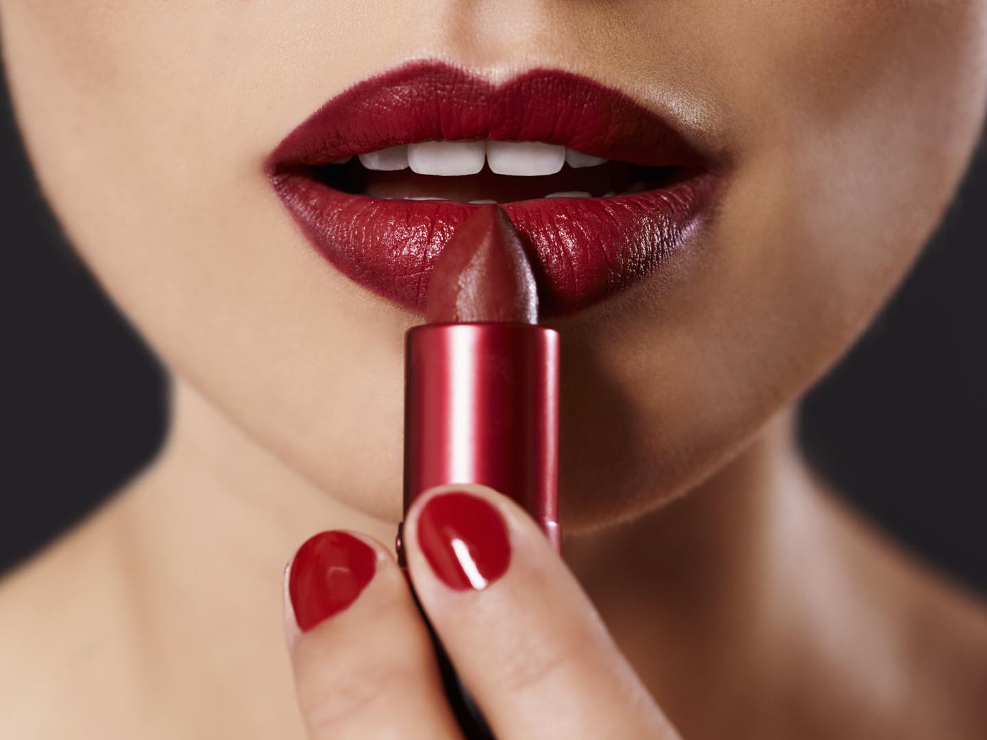 Closeup image of a woman applying lipstick