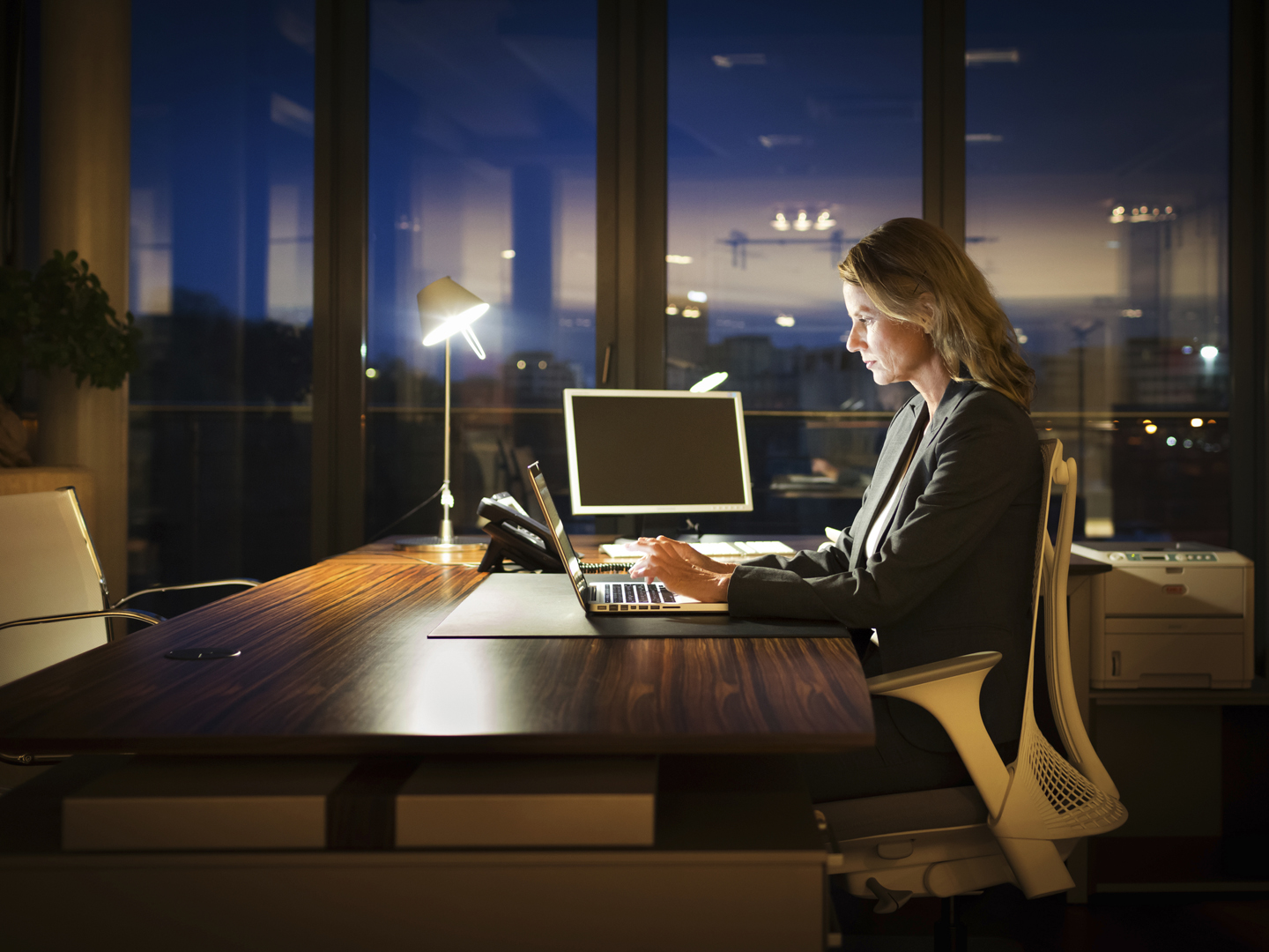 Mature business woman working late in front of a laptop.