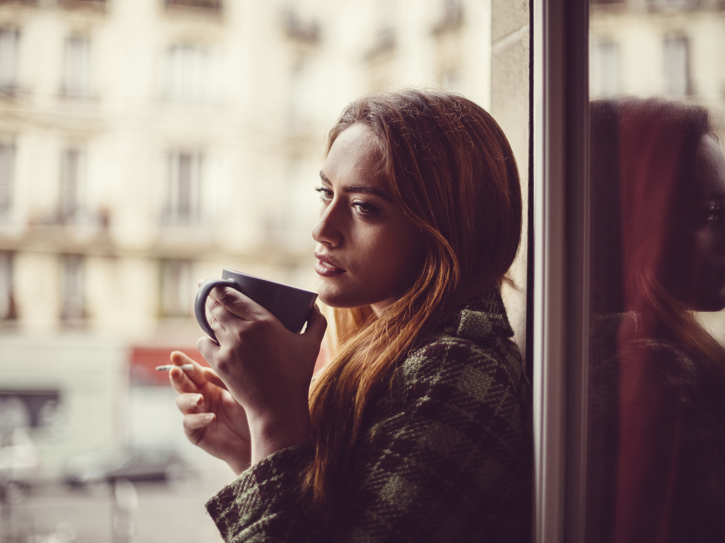 Thoughtful woman smoking cigarette and drinking coffee