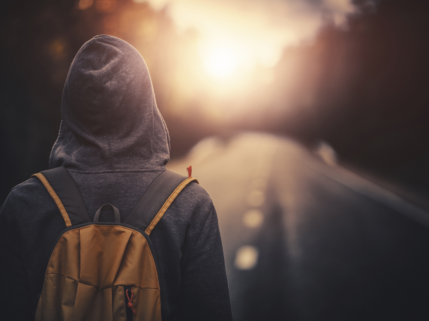 Traveler with backpack walking forward alone at sunset. Stock photo.