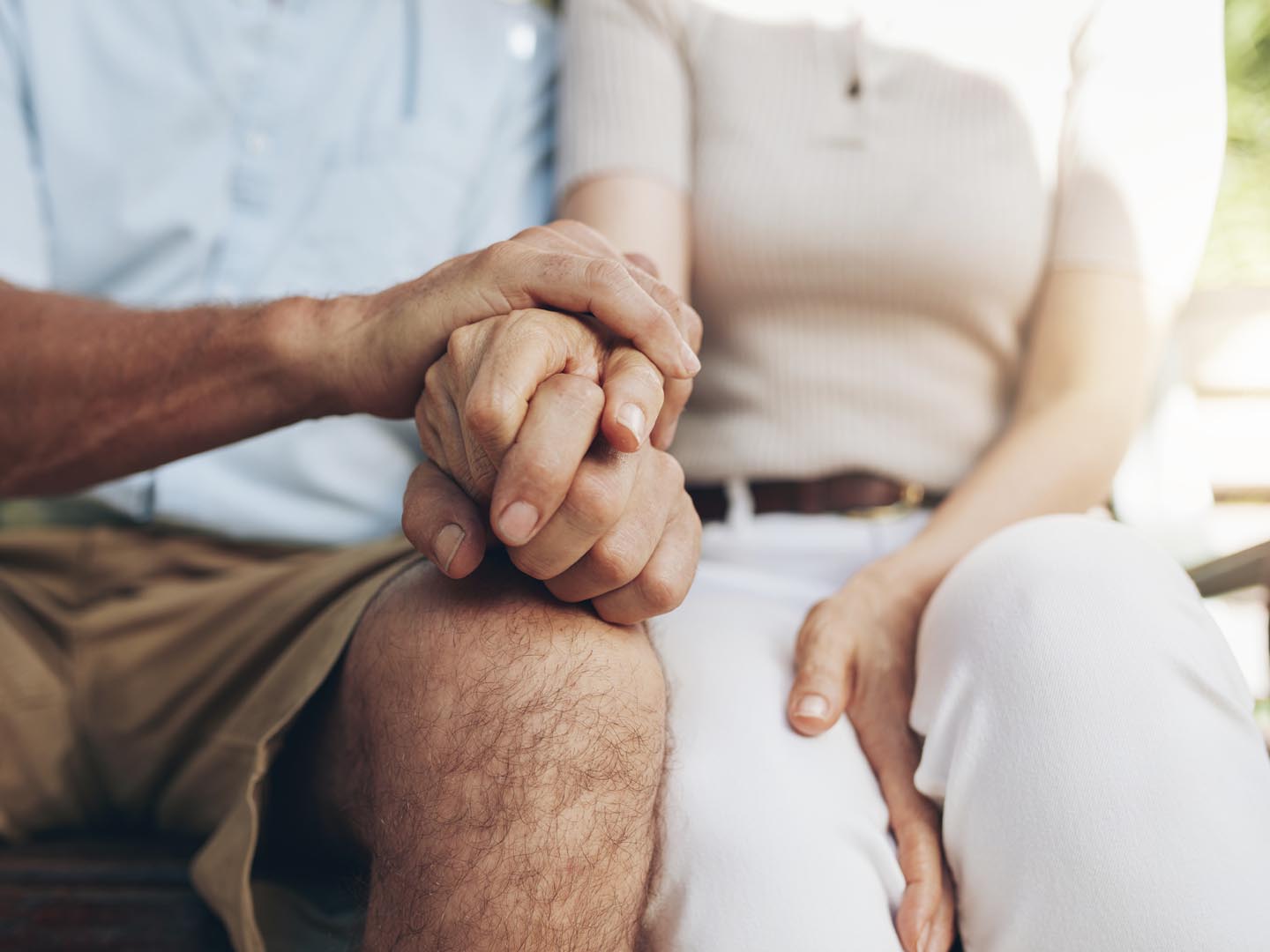 Close up shot of senior couple holding hand. Loving couple sitting together and holding hands. Focus on hands.