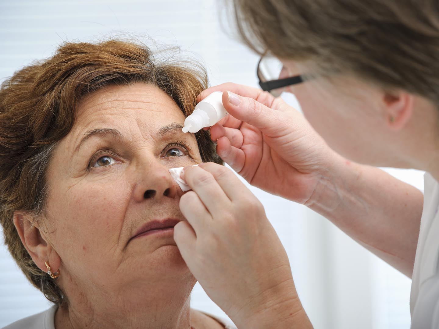 Doctor helps the patient and gives the eye drops