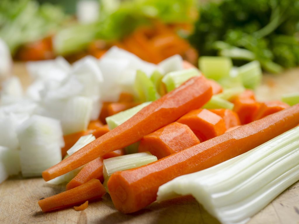 Chopping block with vegetables being prepared for cooking - Stock Photo