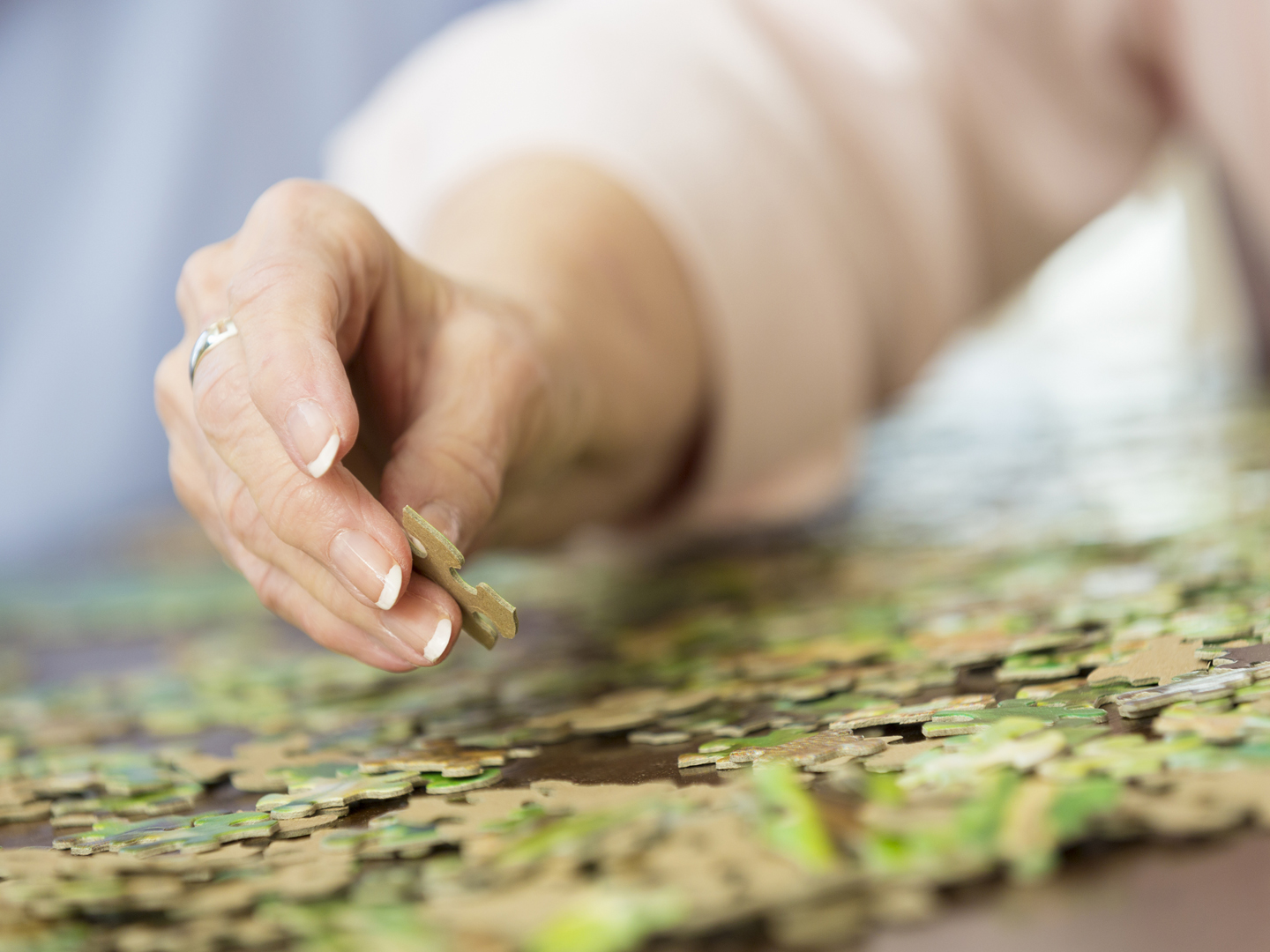Close up of senior woman&#039;s hand putting together puzzle