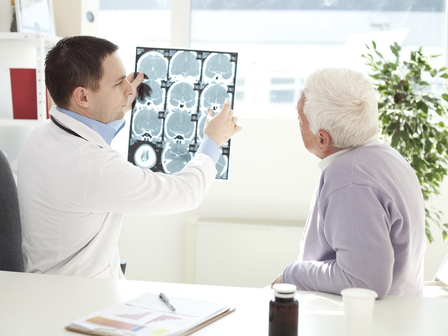 Senior man at doctor&#039;s office. Doctor analyzing a CT scan of head