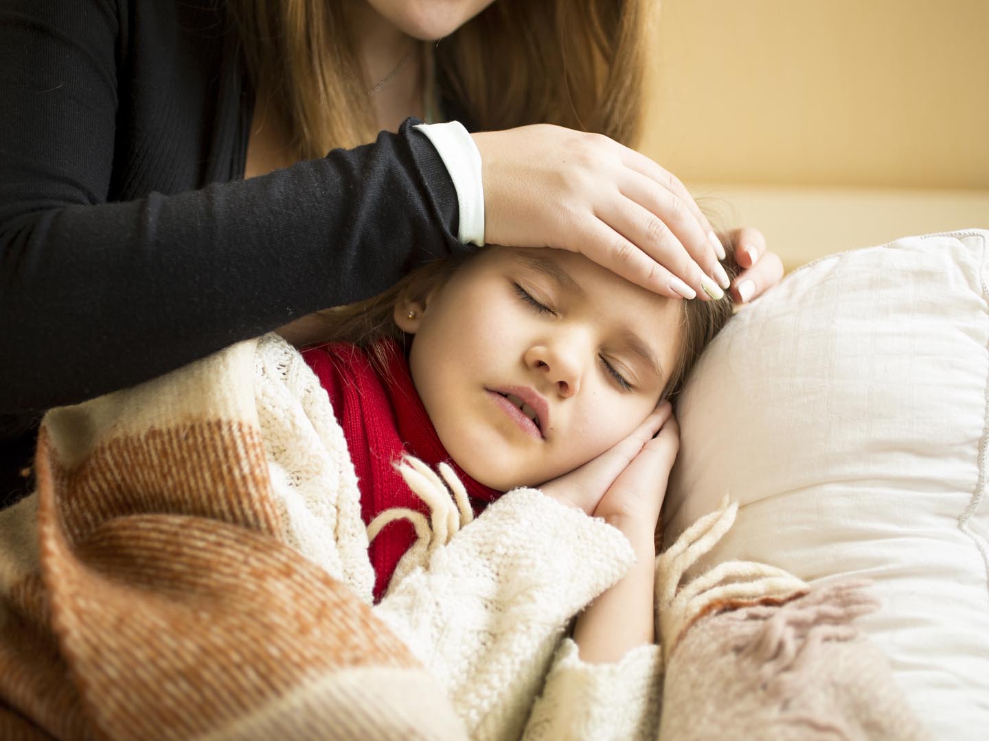 Closeup photo of caring mother holding head on sick daughter forehead