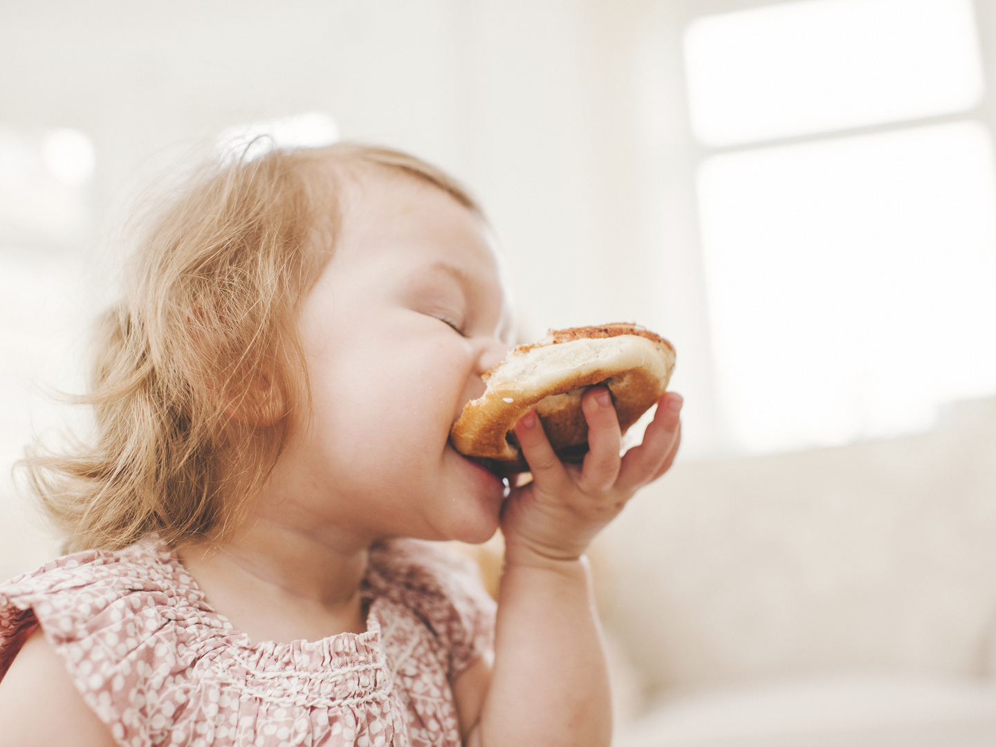 Cute baby girl eating cinnamon bun