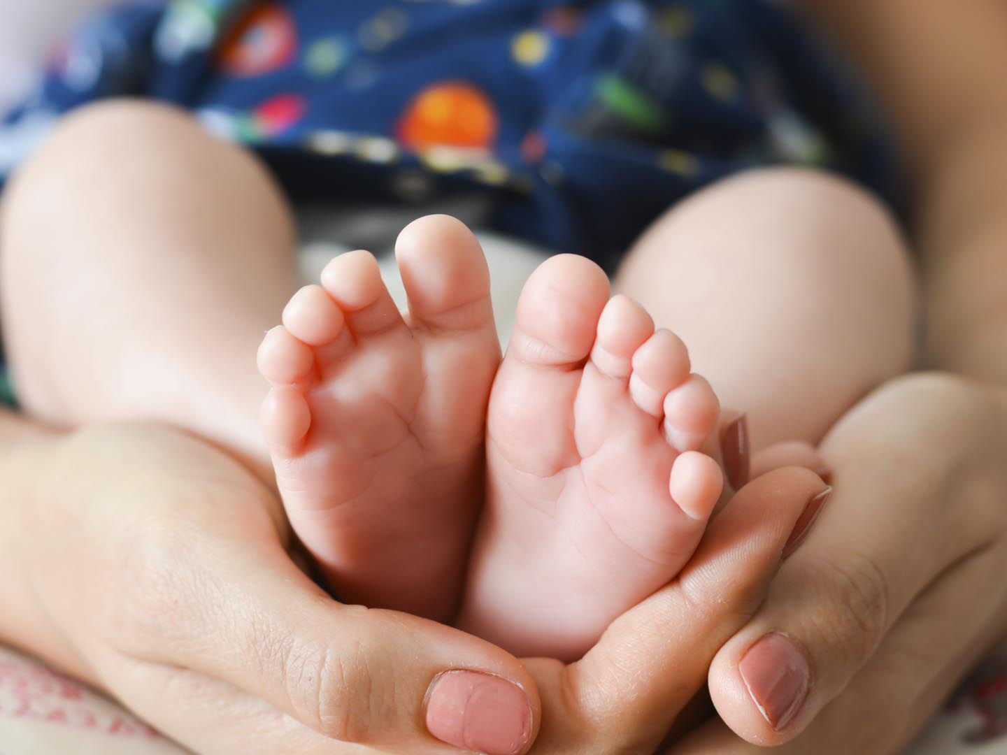 Mother holding baby feet in her palms