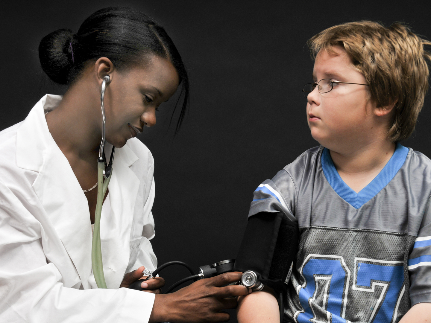 A beautiful young doctor taking a childs blood pressure