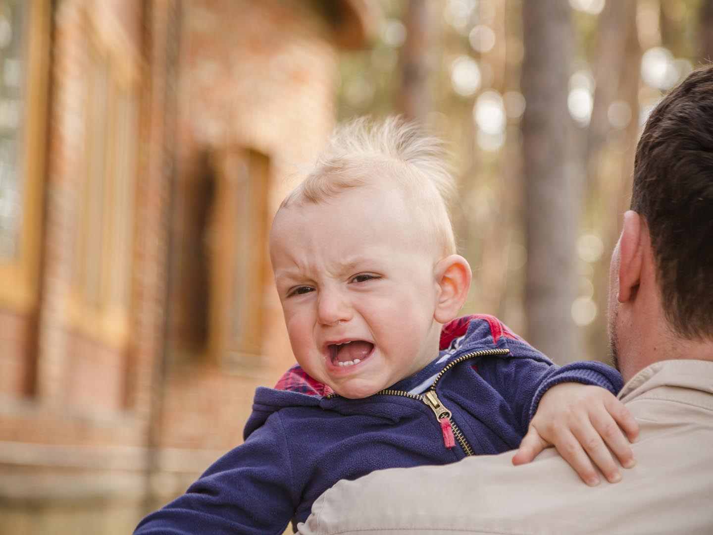 Baby boy crying on his father shoulder, copy space