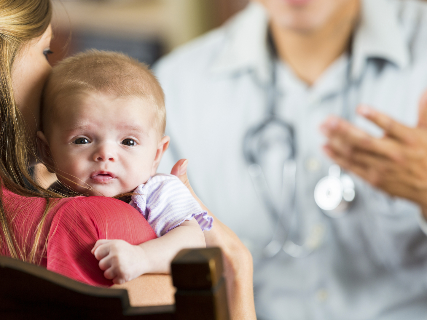 Mother holding baby with cystic fibrosis during pediatric appointment