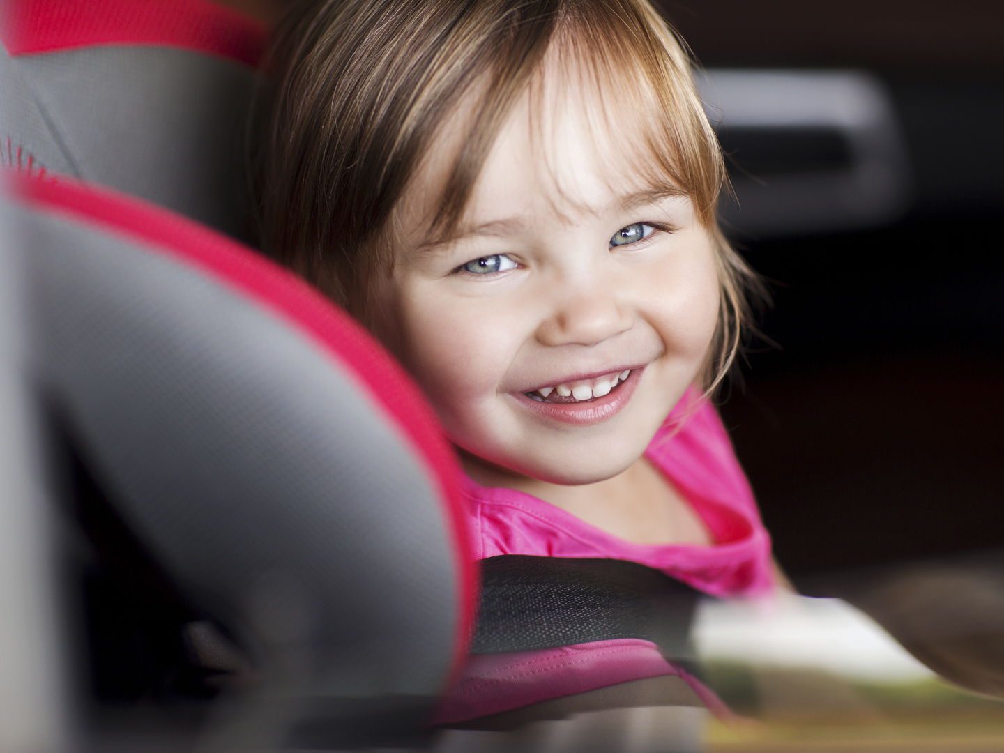 transport, safety, childhood road trip and people concept - happy little girl sitting in baby car seat