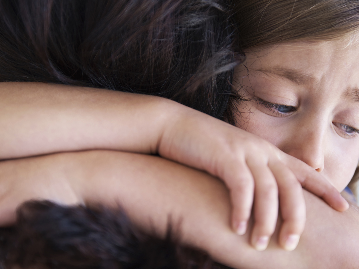 Closeup shot of a upset little girl hugging her mom around the neck