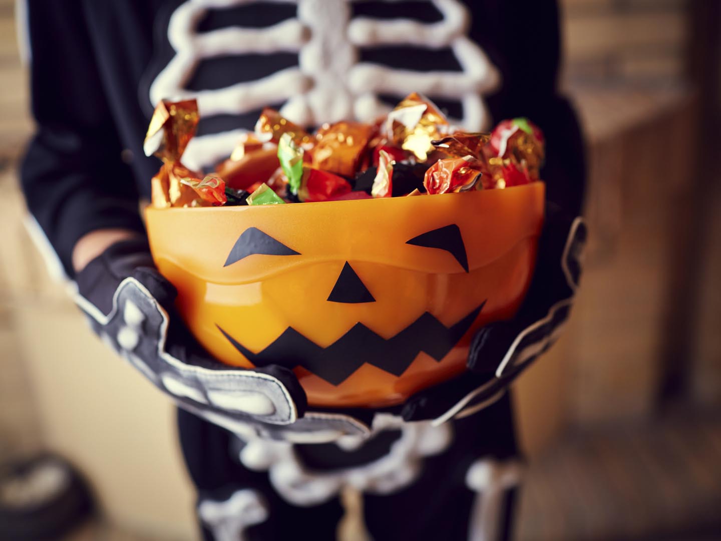 Boy in skeleton costume holding bowl full of candies