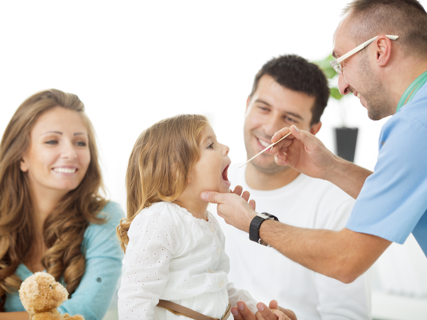 Cheerful family with little girl at doctors office. Doctor examine girls for sore throat. Father holding little girl during examining.