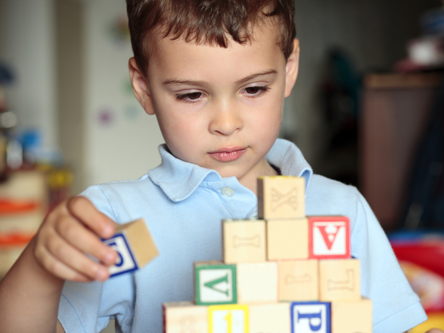 Child with autism deciding where is the best place to put his block. Shall he build it higher?