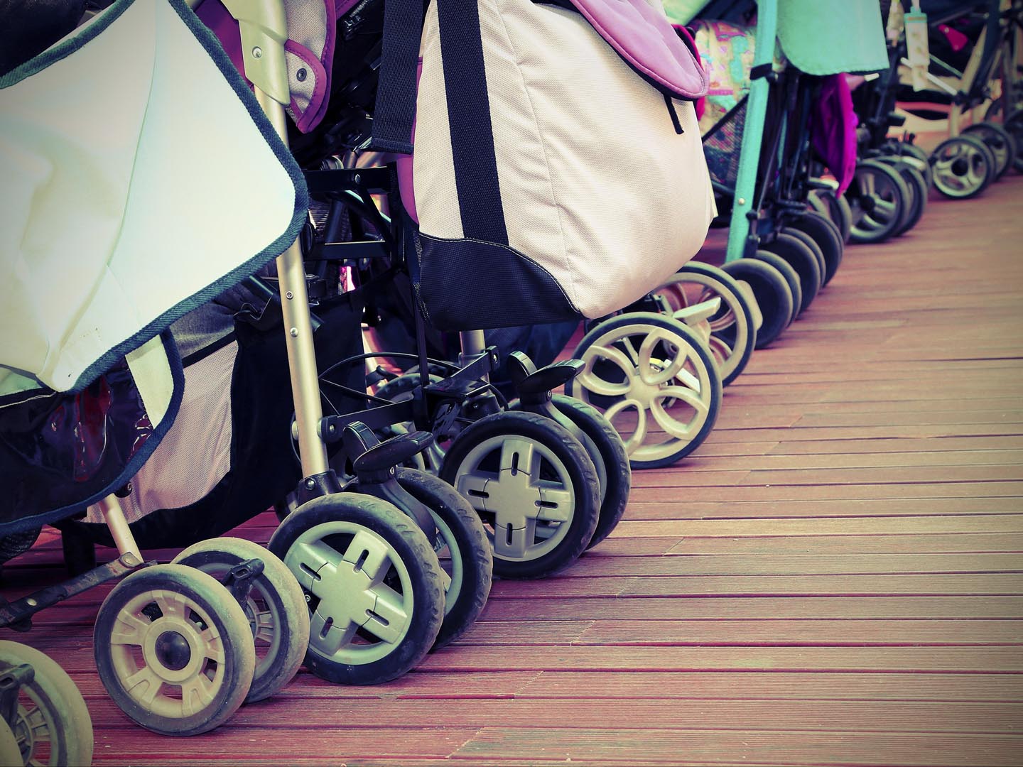 many strollers for toddlers parked on the parquet floor of wood