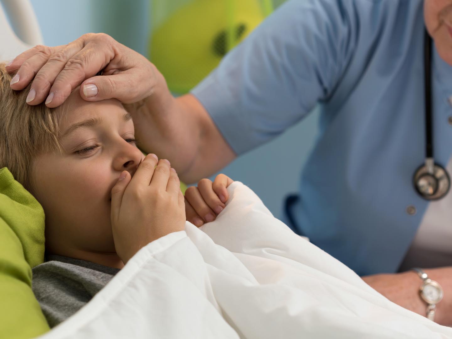 Close-up of coughing toddler lying in hospital bed