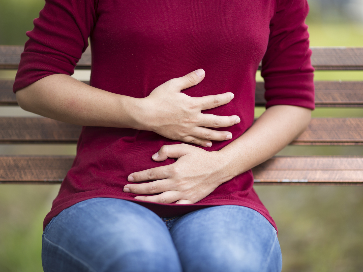 Woman Has Stomach Ache Sitting on Bench at Park