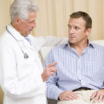 Doctor giving middle-aged man checkup in exam room