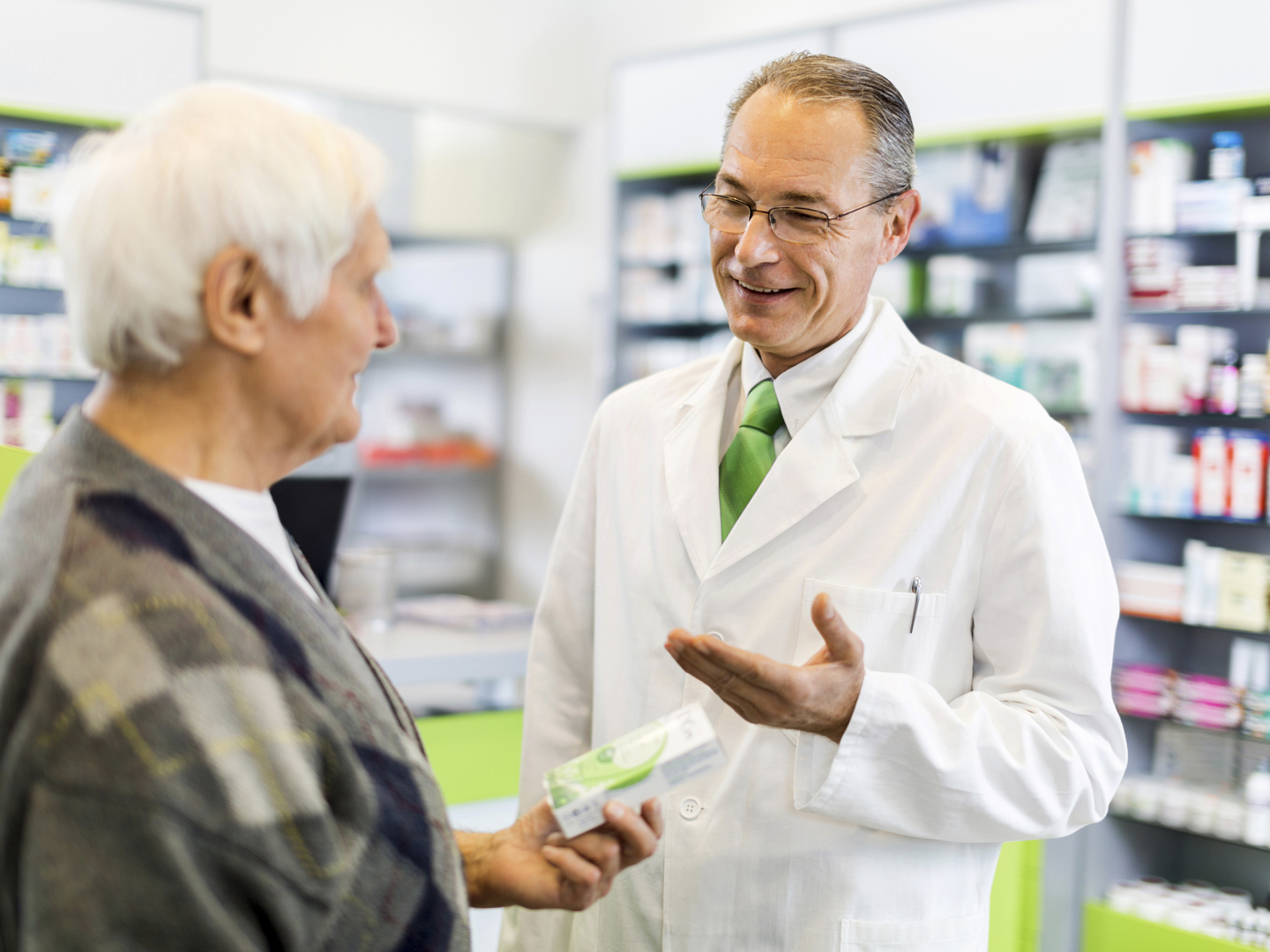 Mature pharmacist talking to senior man in a pharmacy.