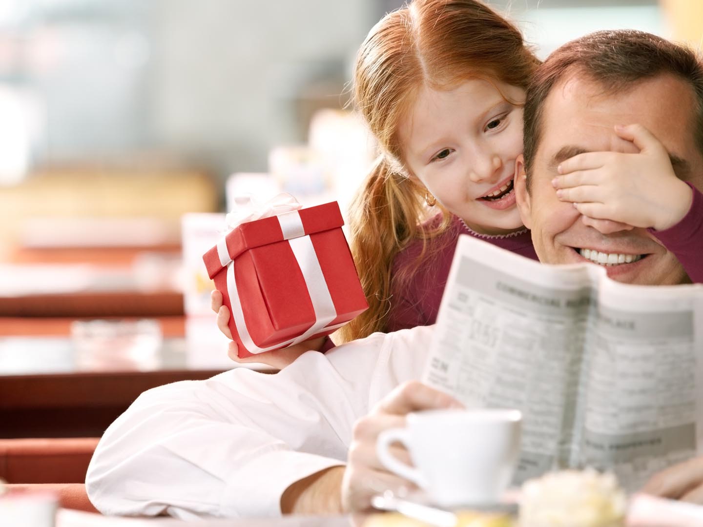 Little daughter giving a gift box to her father