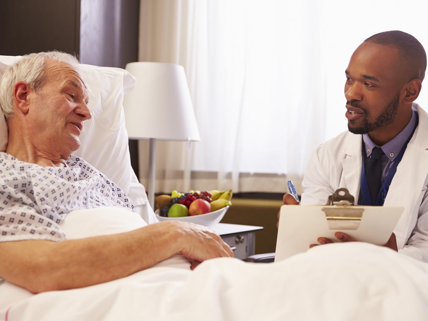 Doctor Talking To Senior Male Patient In Hospital Bed