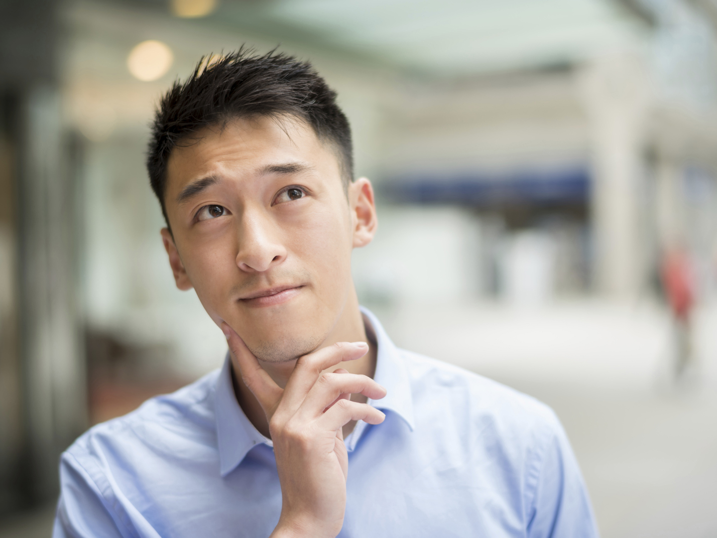 Thoughtful Asian business man in his 20s looking up