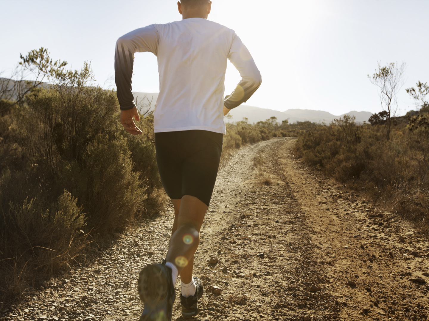 Rear view of man in sportswear running on gravel path