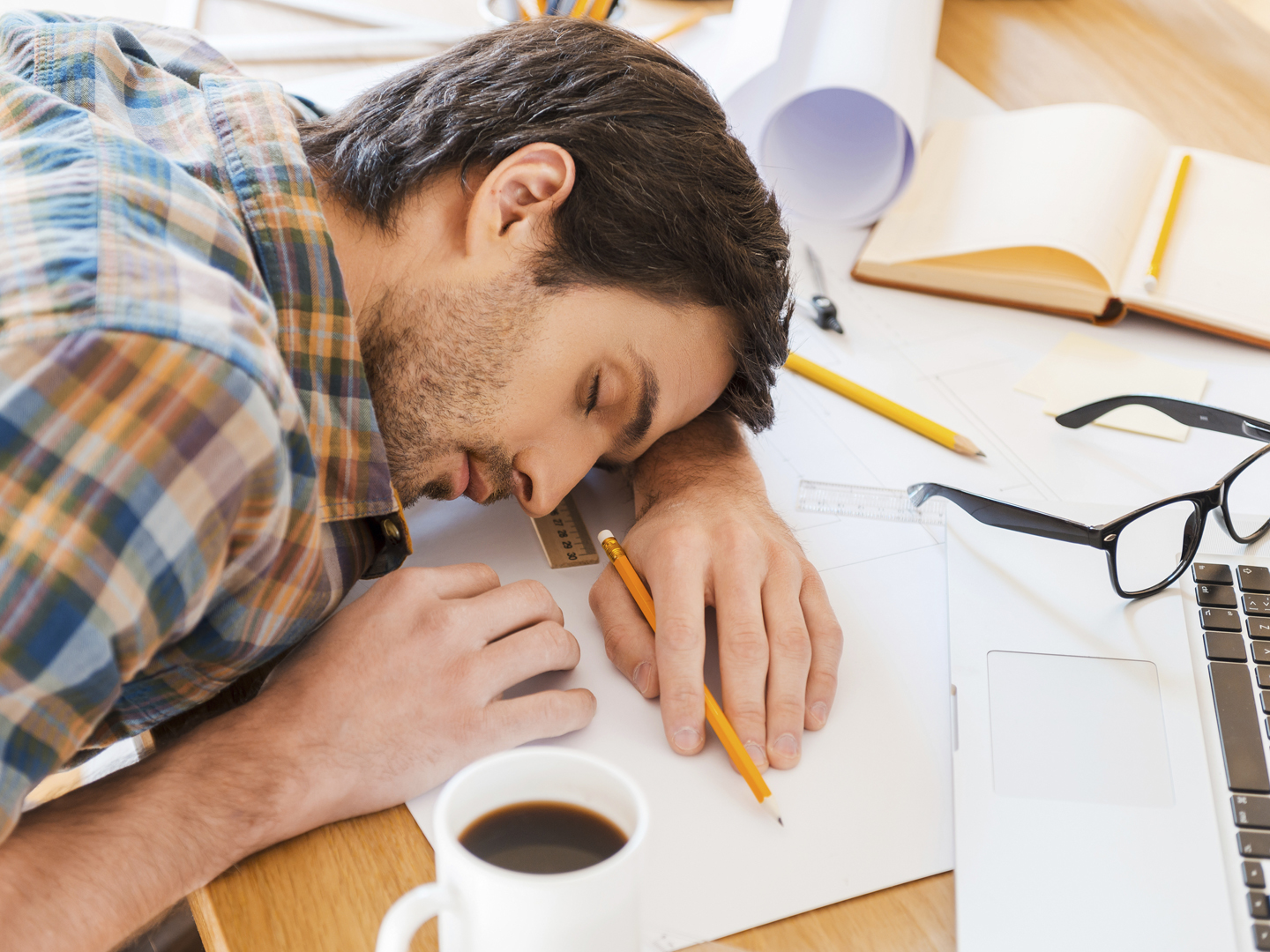 Top view of young man sleeping while sitting at his working place