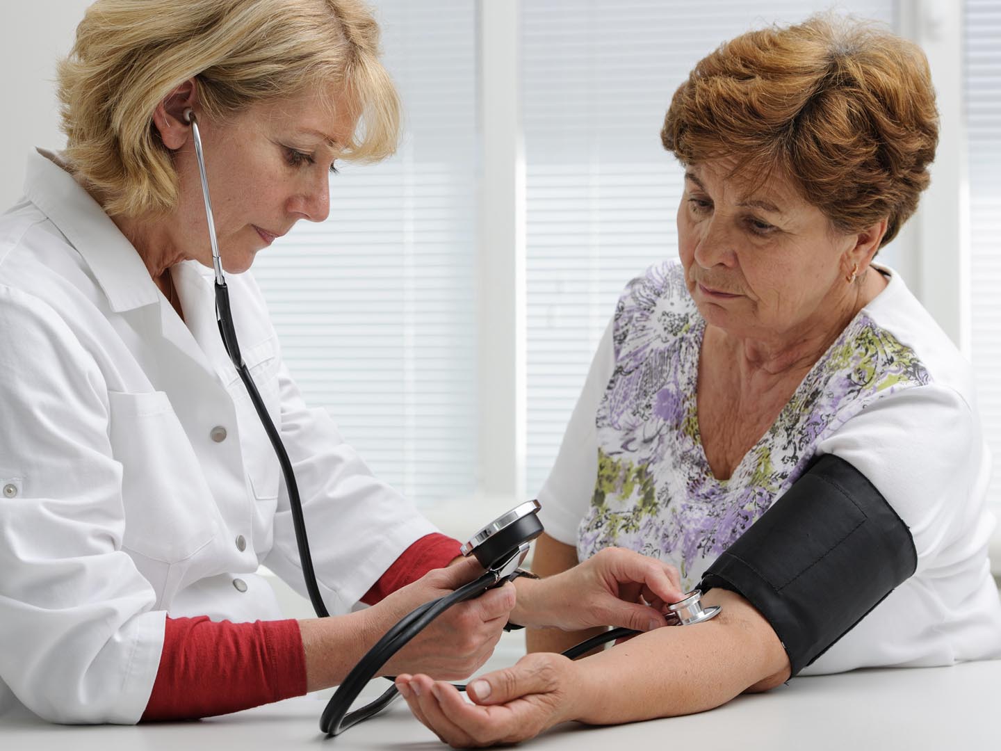 Doctor measuring blood pressure of female patient
