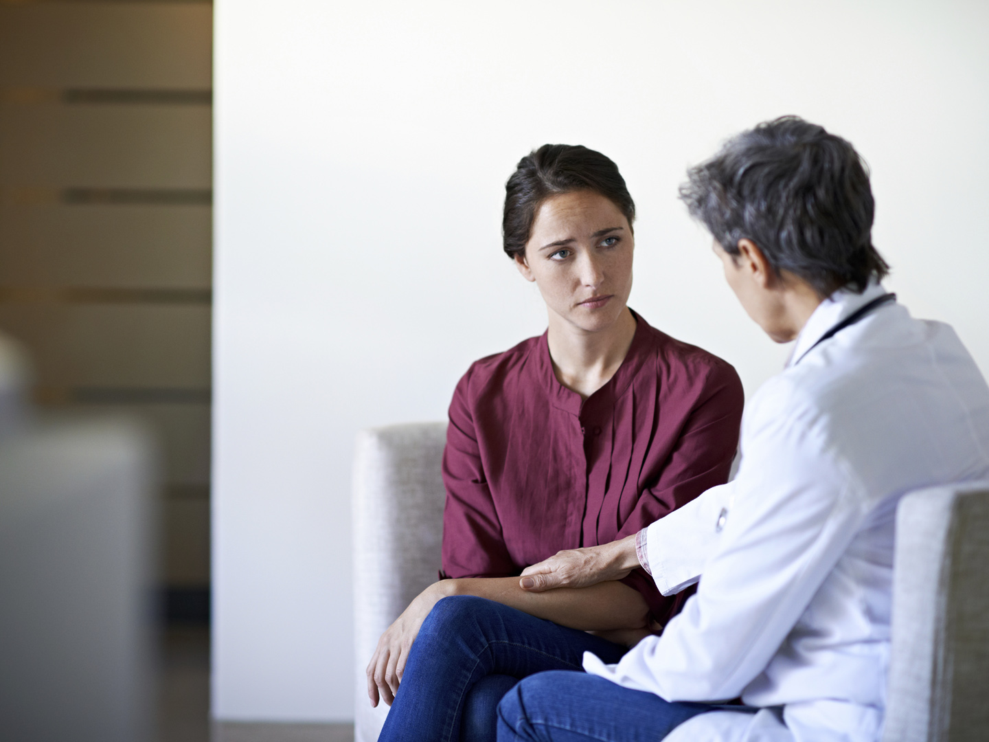 Shot of a compassionate doctor comforting a young woman in a hospital waiting room