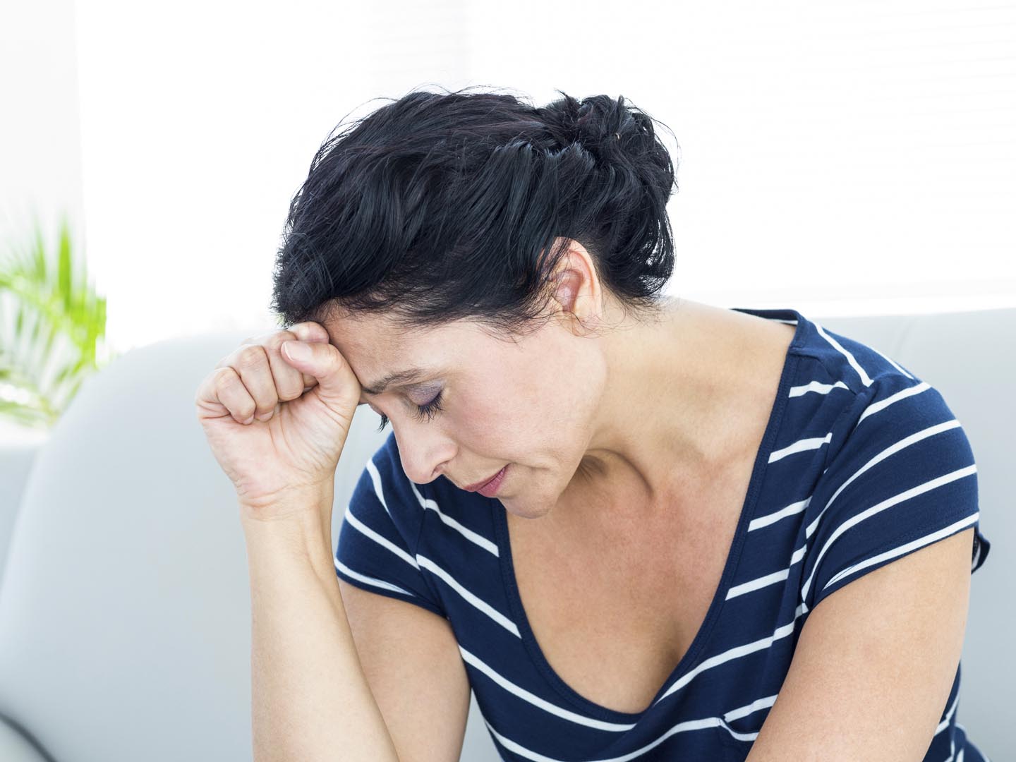 Unhappy woman sitting on the couch on white background