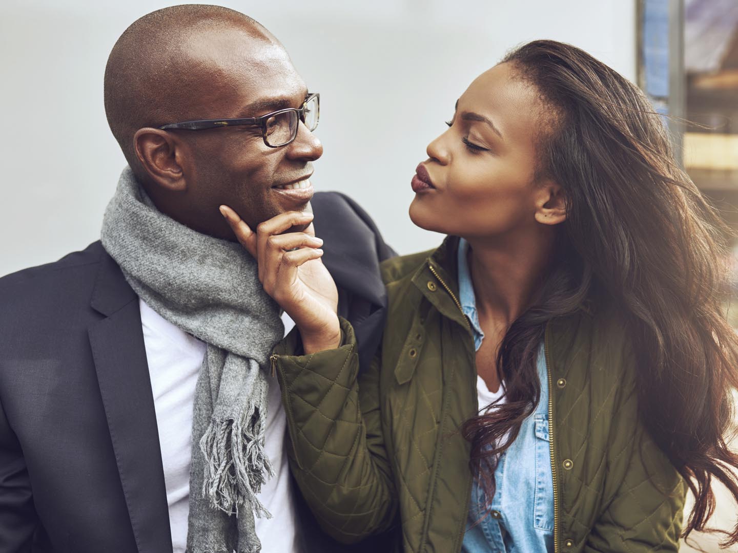 Flirting young African American woman pursing her lips for a kiss and caressing the face of a handsome man in glasses as they enjoy a date together