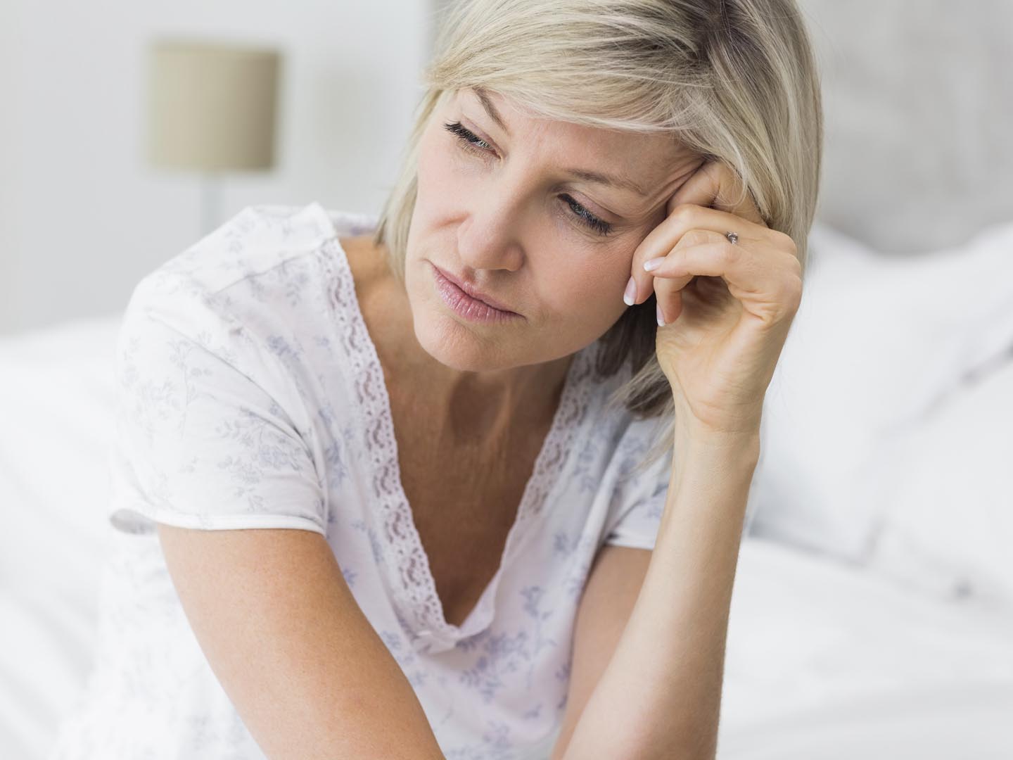 Closeup of a tensed mature woman sitting in bed at home