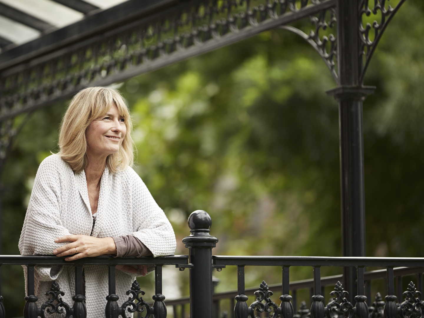 Shot of a mature woman leaning against the railing of her front porch
