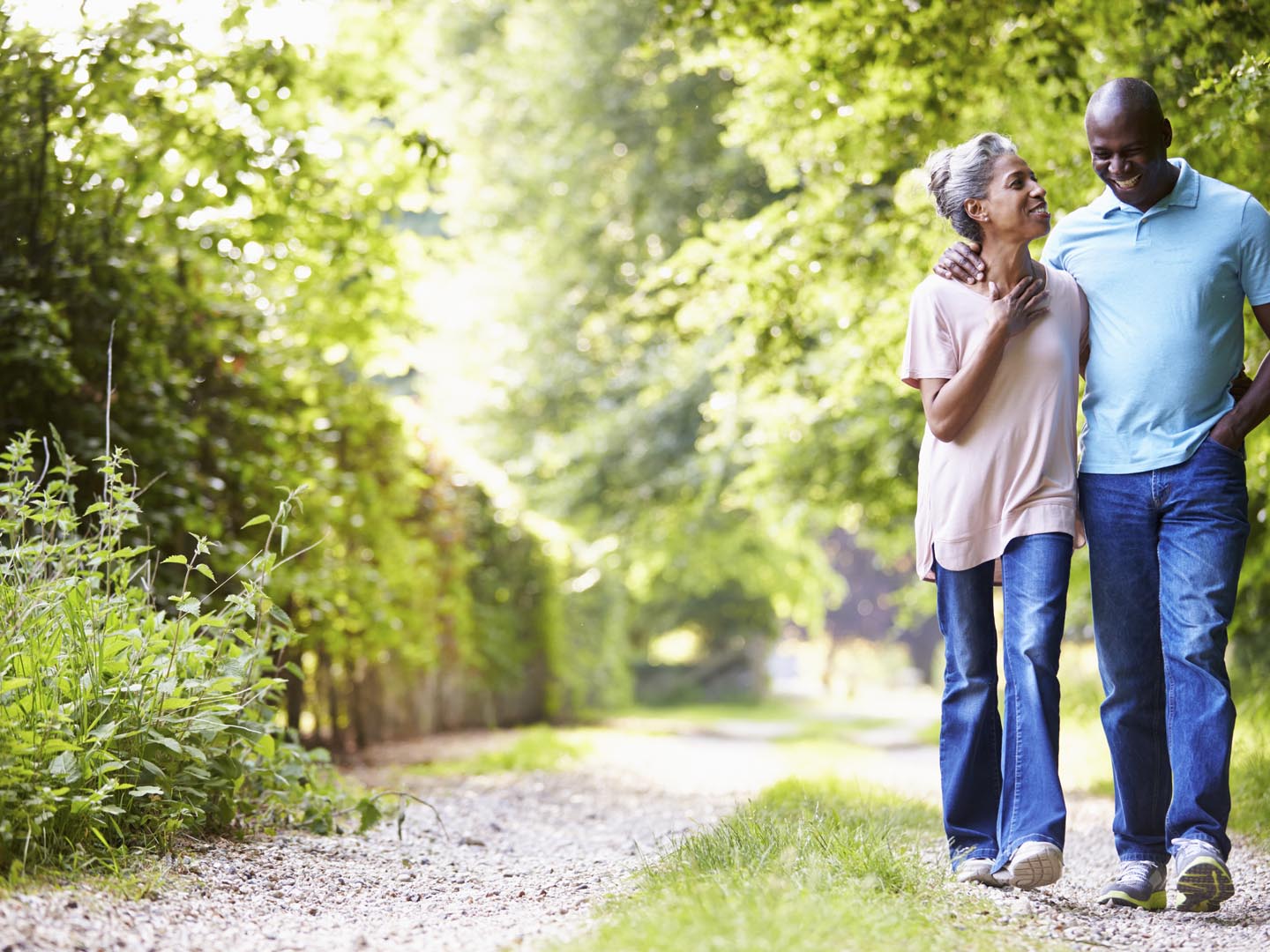 Mature African American Couple Walking In Countryside On Sunny Day