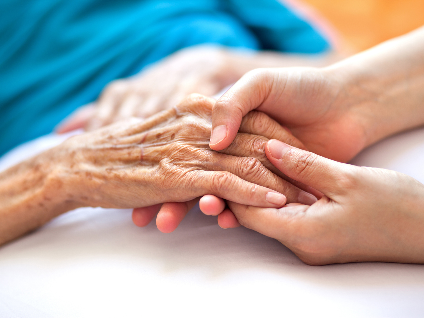 Woman holding senior woman&#039;s hand on bed