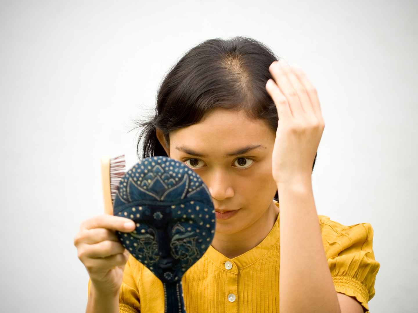 Lifestyle portrait of pretty asian young woman dressing with antique mirror and comb on hands, ready to go out.