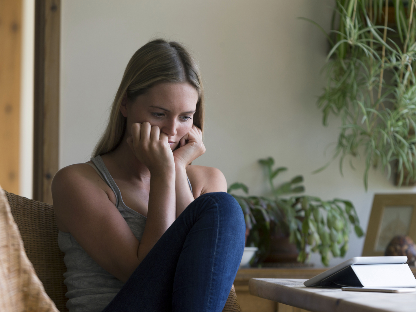 Woman at home looking stressed at her dining room table. She has a digital tablet and a smartphone in front of her.Woman at home looking stressed at her dining room table. She has a digital tablet and a smartphone in front of her.