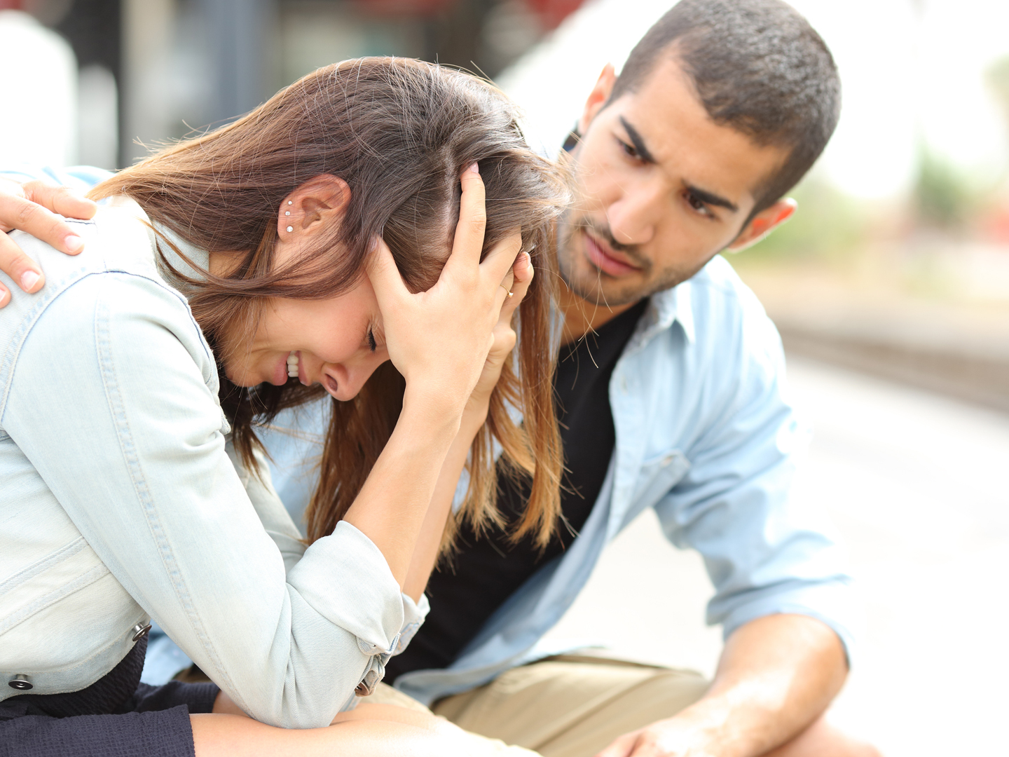 Side view of a muslim man comforting a sad caucasian girl mourning in a train station