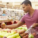 Man At Fruit Counter In Supermarket Putting Fruit Into A Bag