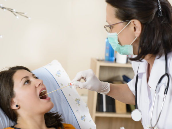 Young woman at doctor being tested for pain in the throat