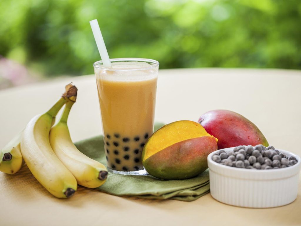 Mango smoothie bubble tea with fruit and tapioca pearls in the garden