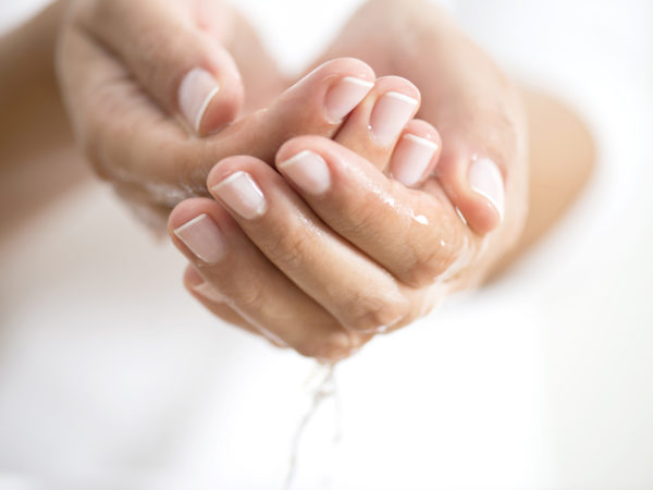 Caucasian female is holding water in hands, horizontal