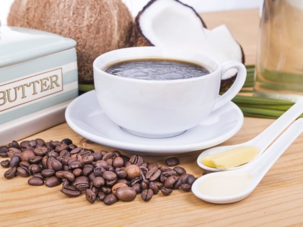 Closeup of bulletproof coffee with cold pressed extra virgin coconut oil and grass fed organic butter on wooden table, part of ketogenic diet