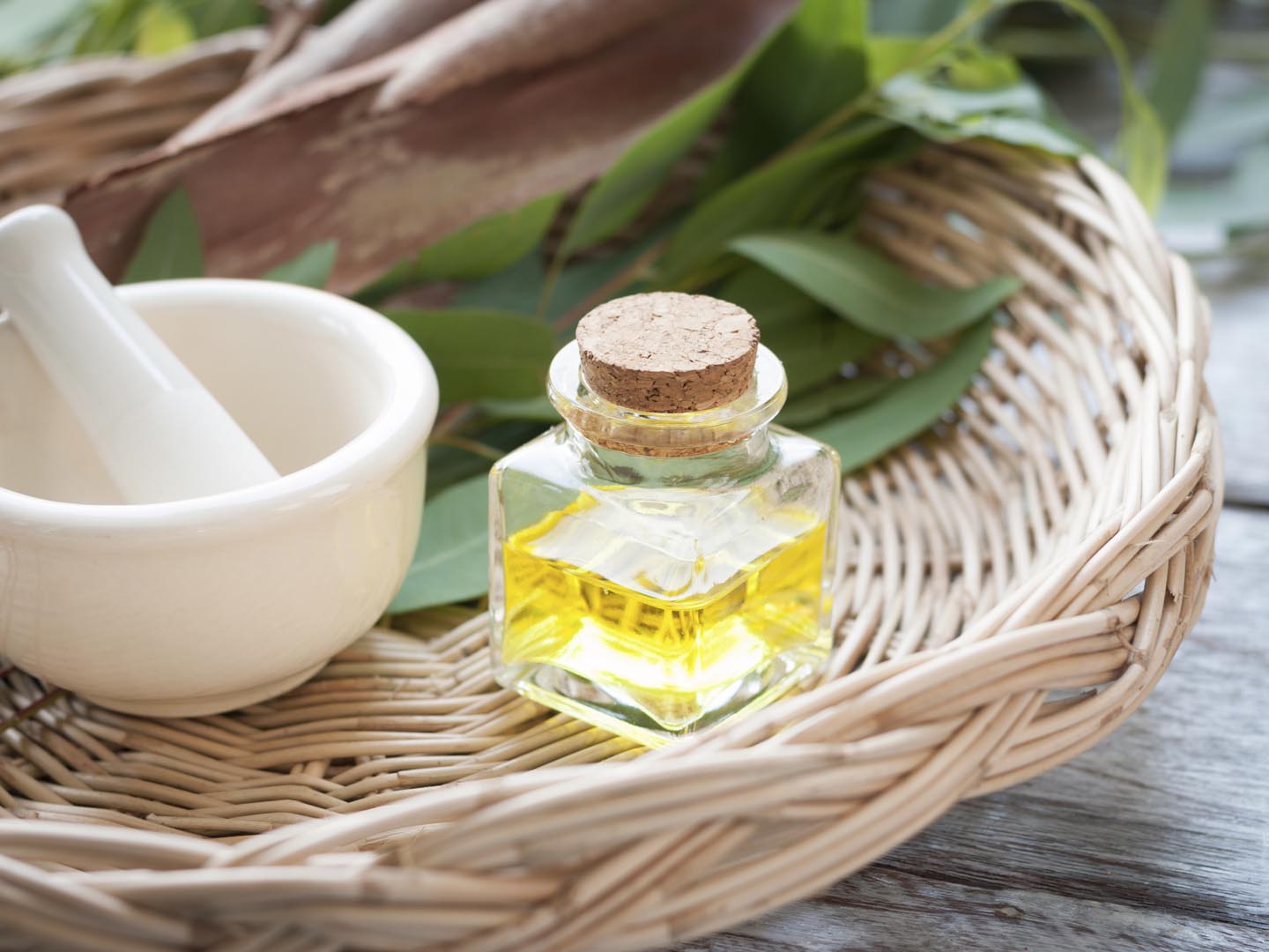 Eucalyptus leaves and essential oil on wooden cutting board.