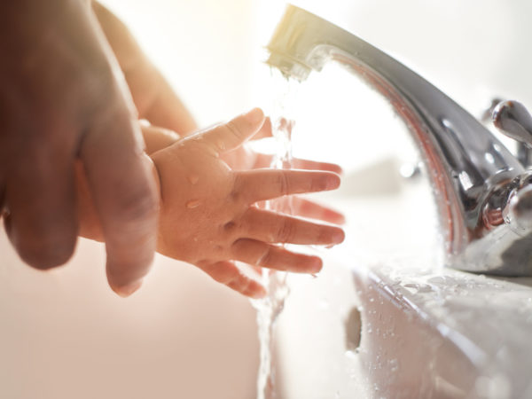 Closeup shot of a father helping his baby girl wash her hands at a tap