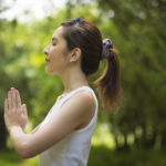 Young Asian woman practicing yoga in a garden. healthy lifestyle and relaxation
