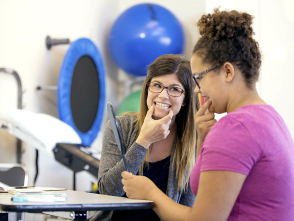 Young adult female therapist doing speech therapy